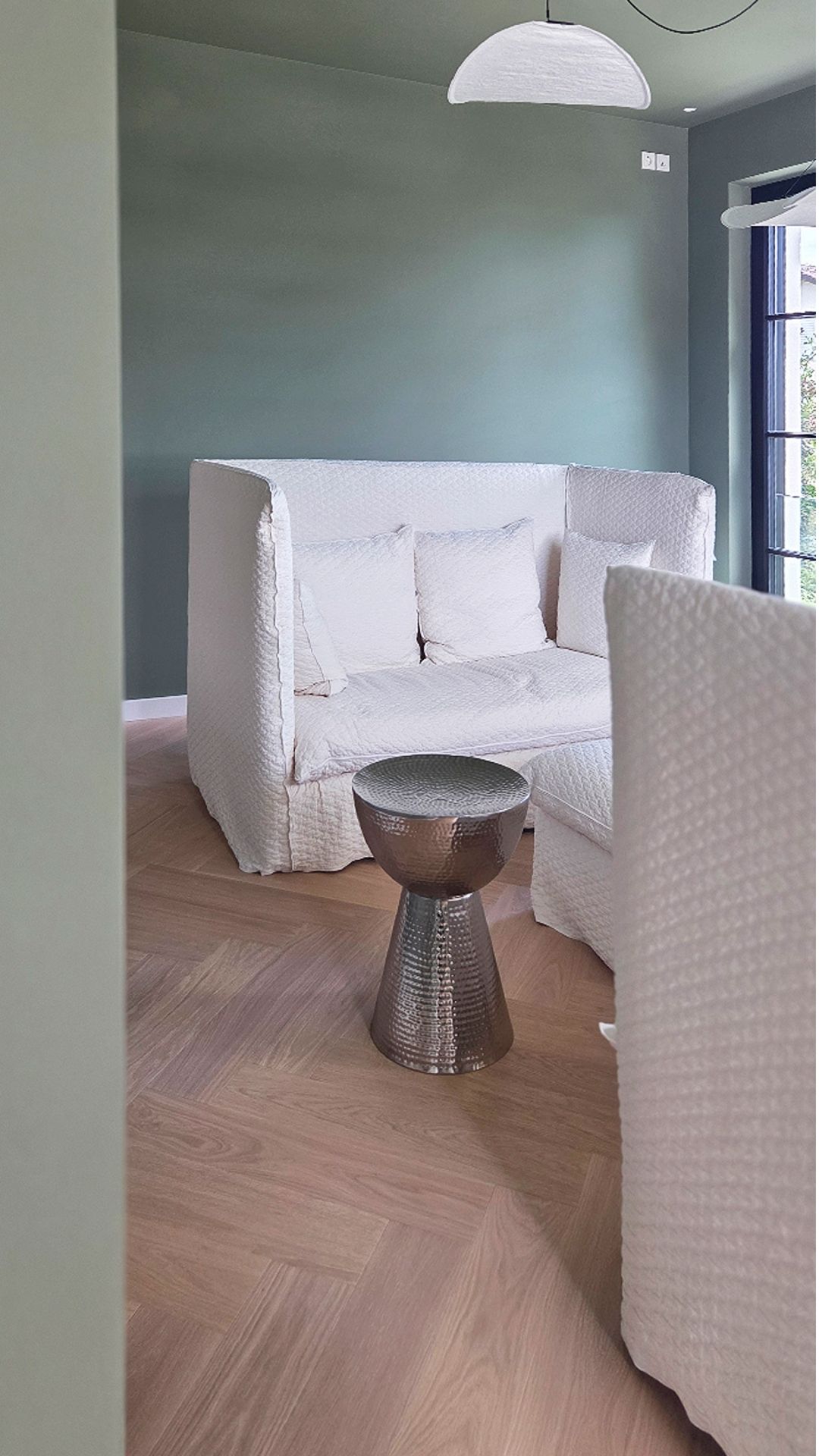 Rückzugszimmer mit salbeigrüner Wand und weißem Hochlehner-Sofa